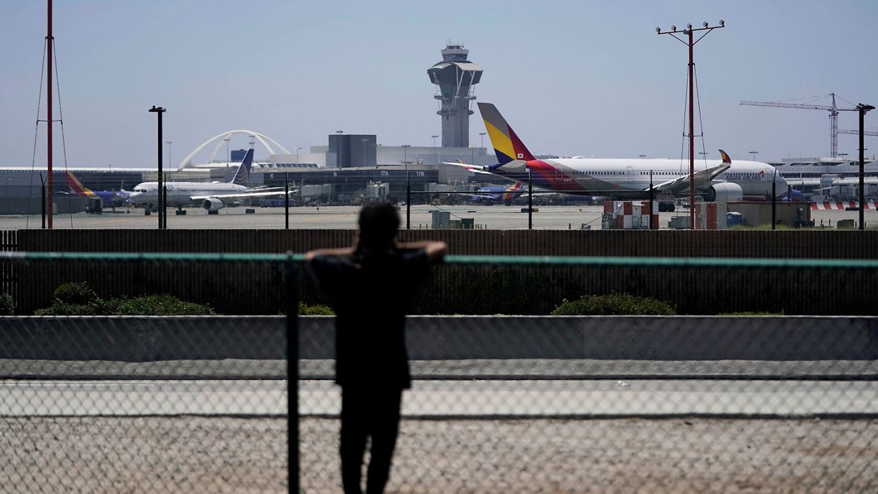 A boy takes pictures of planes taxing to take off at the Los Angeles International Airport in Los Angeles, Friday, July 1, 2022. (AP Photo/Jae C. Hong)