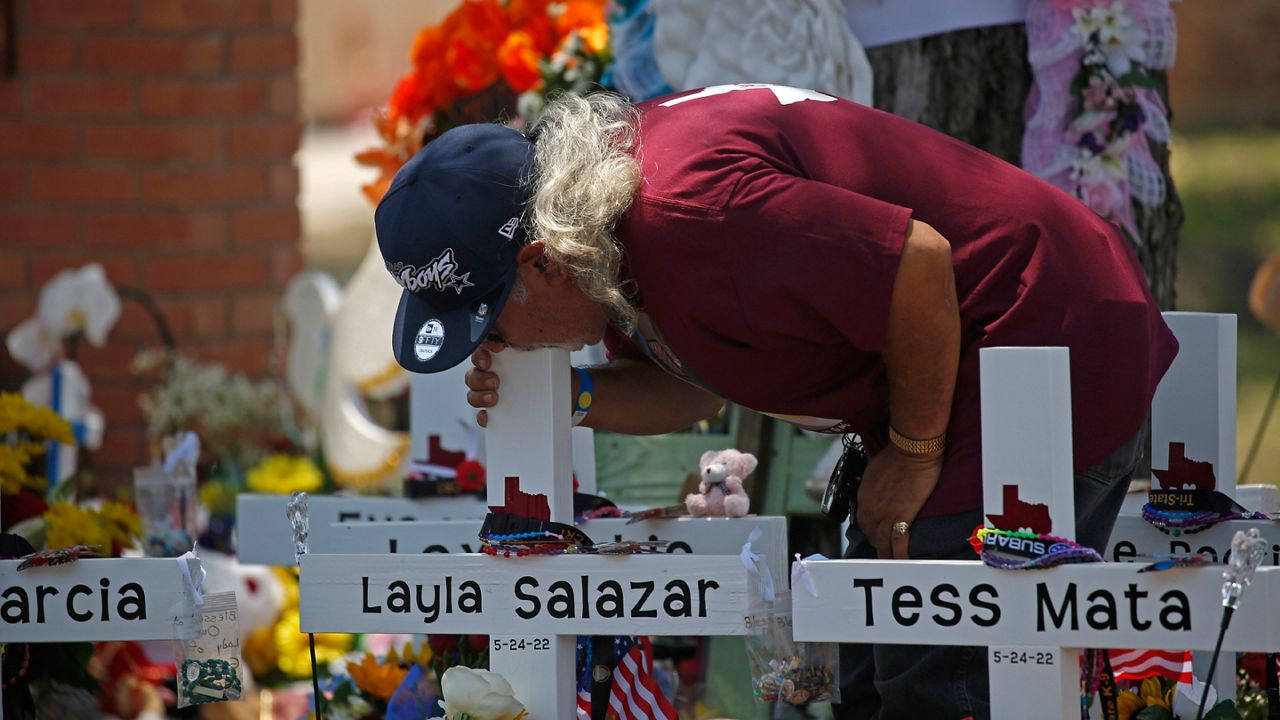 A man kisses the cross of Layla Salazar at a memorial outside Robb Elementary School to honor the victims killed in this week's school shooting in Uvalde, Texas, Saturday, May 28, 2022. (AP Photo/Dario Lopez-Mills)