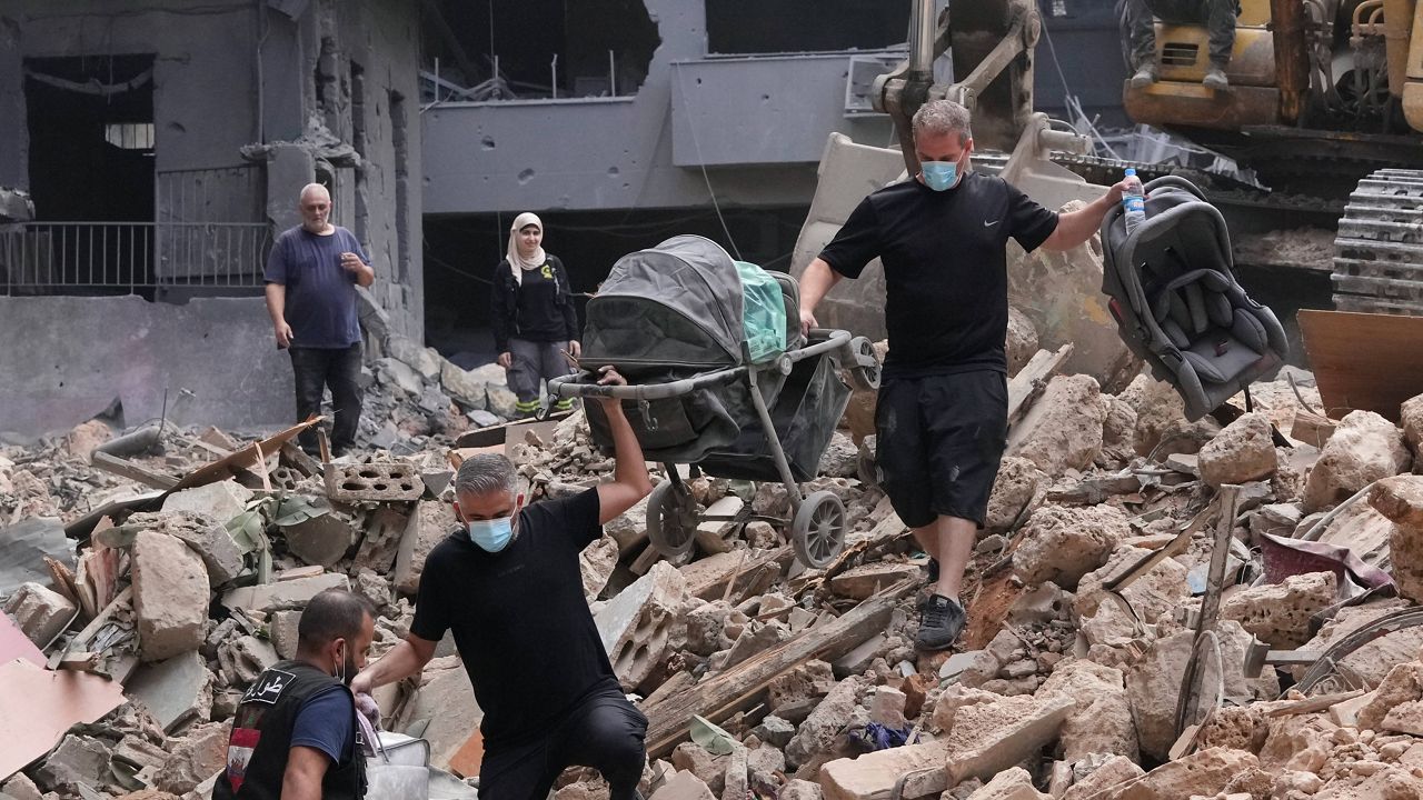 Residents of a building damaged in an Israeli airstrike return to collect their family's belongings at the site of Thursday's Israeli airstrike in Beirut, Lebanon, Saturday, Oct. 12, 2024. (AP Photo/Hassan Ammar)