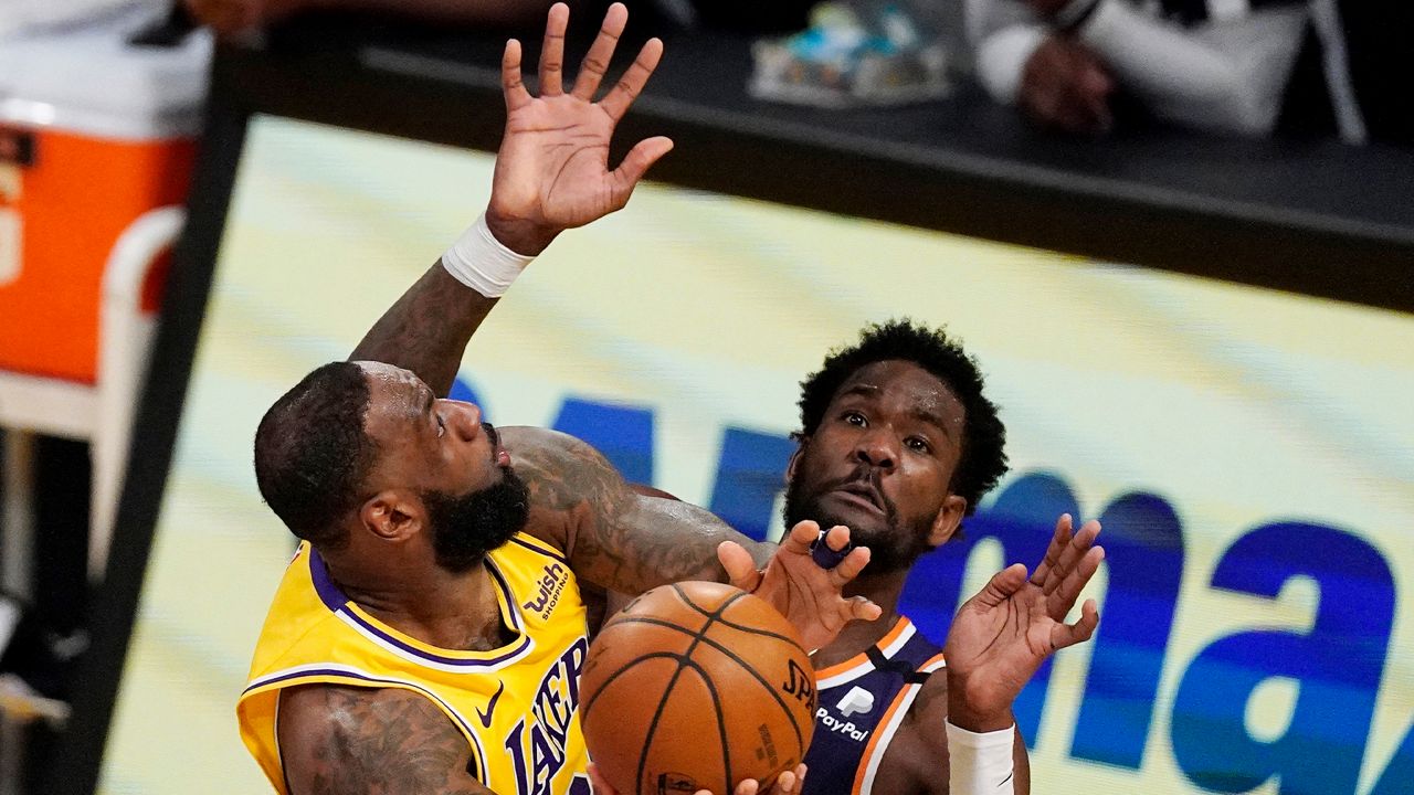 Los Angeles Lakers forward LeBron James, left, shoots as Phoenix Suns center Deandre Ayton defends during the first half of an NBA basketball game Tuesday, March 2, 2021, in Los Angeles. (AP Photo/Mark J. Terrill)