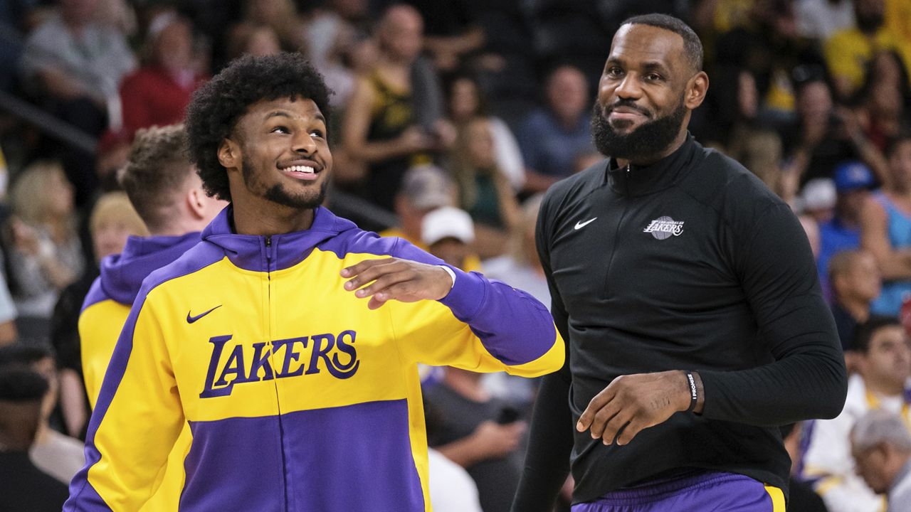 Los Angeles Lakers guard Bronny James, left, and forward LeBron James warm up before a preseason NBA basketball game against the Phoenix Suns, Sunday, Oct. 6, 2024, in Palm Desert, Calif.