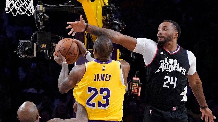 Los Angeles Lakers forward LeBron James, center, shoots as Clippers forward P.J. Tucker, left, and guard Norman Powell defend during the first half of an NBA basketball game Wednesday in LA. (AP Photo/Mark J. Terrill)