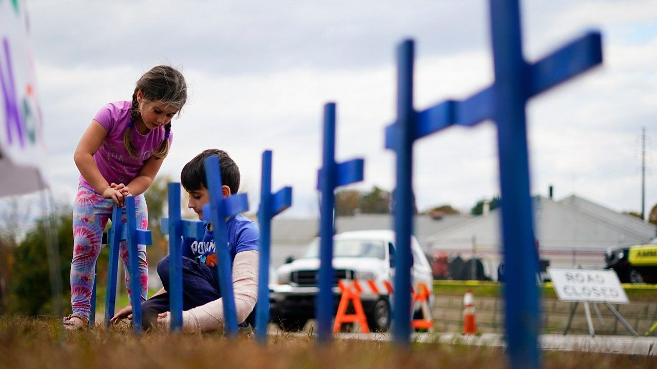 Lucy Allard, 5, and her brother Zeke Allard, 8, plant crosses in honor of the victims of this week's mass shooting in Lewiston, Maine, Saturday, Oct. 28, 2023. The residents of Lewiston are embarking on a path to healing after a man suspected of killing several people earlier this week was found dead. (AP Photo/Matt Rourke)