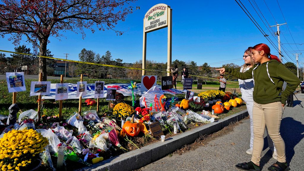 Community members look at a memorial outside Schemengees Bar & Grille about one week after a mass shooting, Nov. 3, 2023, in Lewiston. An independent commission investigating the mass shooting that left 18 people dead in Maine is scheduled to hear from the family of the shooter, Robert Card, for the first time on Thursday, May 15, 2024. (AP Photo/Matt York, File)