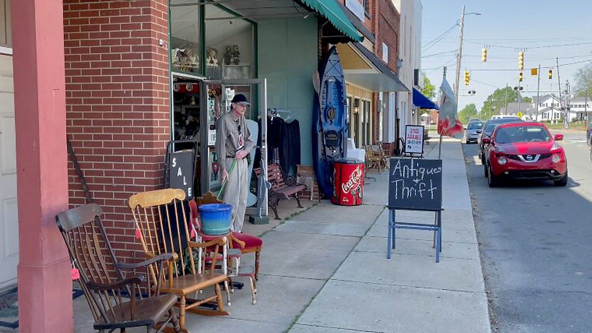 Ronald Alexander, owner of Liberty Emporium & Thrift, Computer Services, sweeps entrance of the store. (Spectrum News 1/Chelsea Floyd)