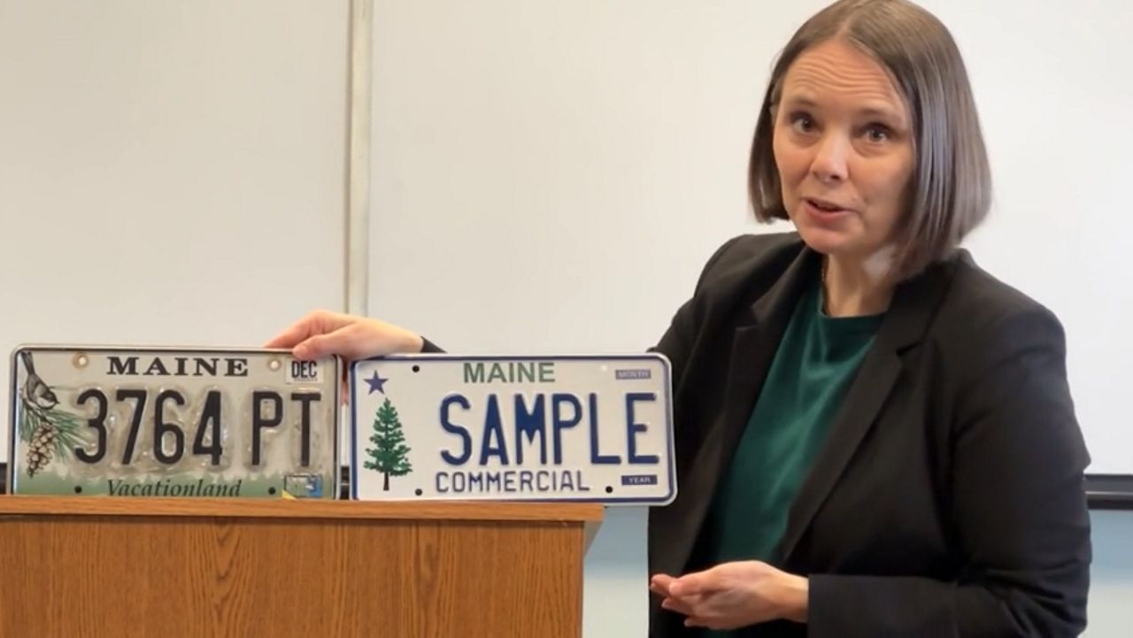 Maine Secretary of State Shenna Bellows compares the current standard license plate, left, with the one unveiled Monday. (Spectrum News/Sean Murphy)