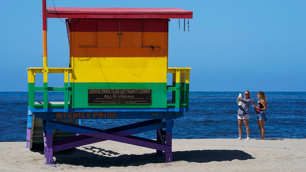 Women take a selfie near the Venice Pride Flag lifeguard tower on Wednesday, May 13, 2020, in the Venice Beach area of Los Angeles. (AP Photo/Ashley Landis)