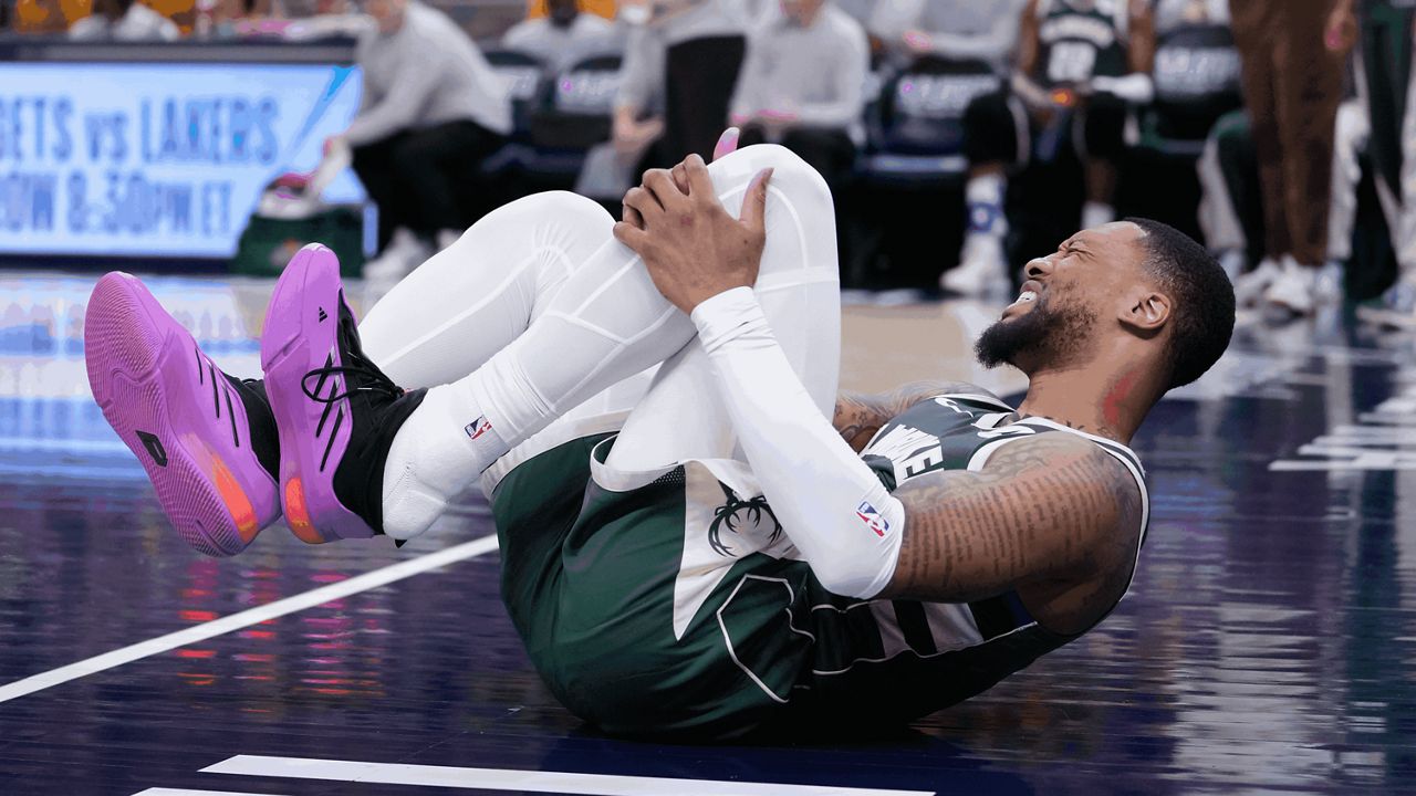 Milwaukee Bucks guard Damian Lillard (0) grabs his leg after being injured