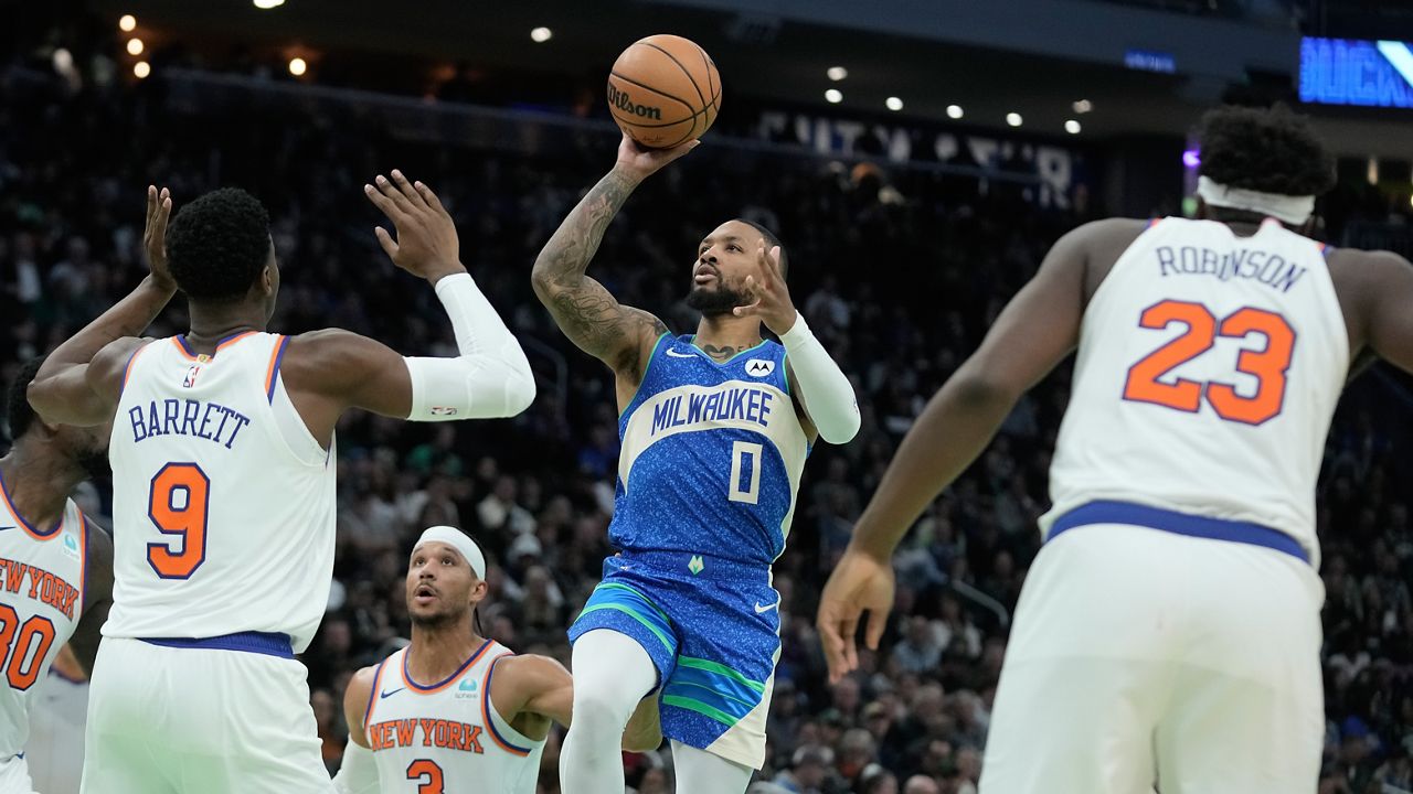 Milwaukee Bucks' Damian Lillard shoots past New York Knicks' RJ Barrett and Mitchell Robinson