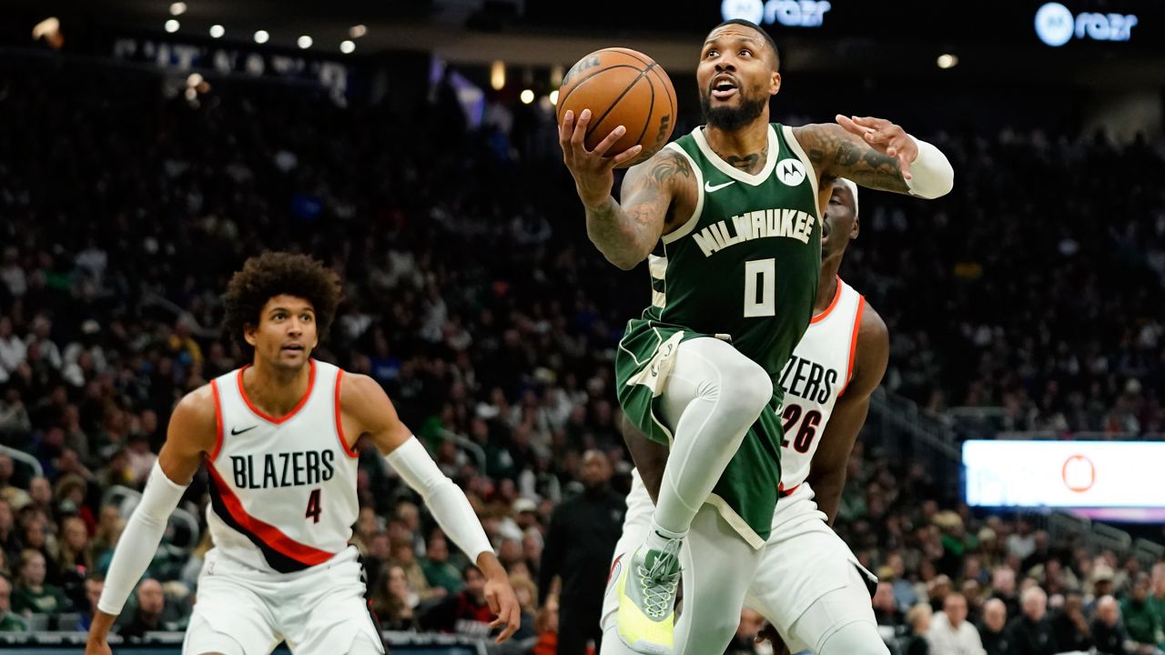 Milwaukee Bucks' Damian Lillard (0) shoots past Portland Trail Blazers' Duop Reath (26) and Matisse Thybulle (4) 