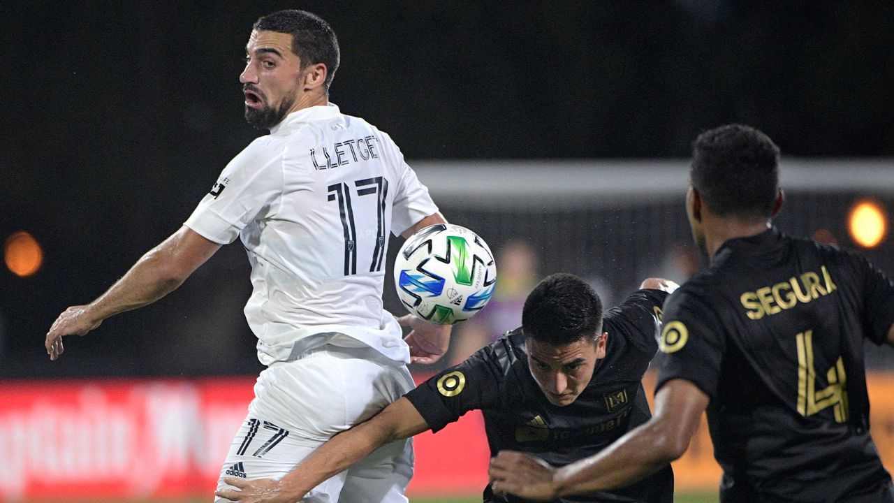 LA Galaxy midfielder Sebastian Lletget (17) competes for the ball with Los Angeles FC midfielder Eduard Atuesta (20) and defender Eddie Segura (4) during the first half of an MLS soccer match Saturday, July 18, 2020, in Kissimmee, Fla. (AP Photo/Phelan M. Ebenhack)