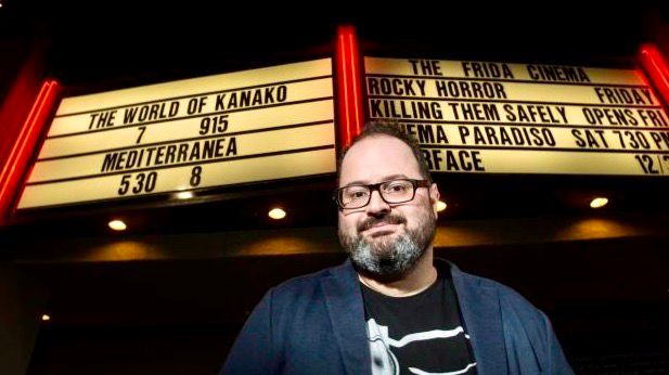 Logan Crow, the executive director of the Frida Cinema, stands in front of its marquee in Santa Ana