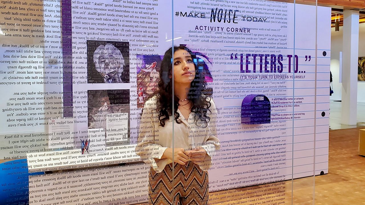 Arabella Varieur of Fullerton looks at the Make Noise Today art exhibit at the Billie Jean King Library in Long Beach (Spectrum News/Joseph Pimentel)