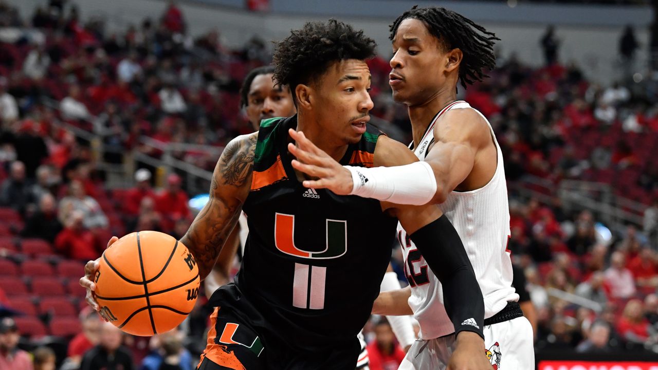 Miami guard Jordan Miller (11) tries to get past Louisville forward JJ Traynor (12) during the first half of an NCAA college basketball game in Louisville, Ky., Sunday, Dec. 4, 2022. (AP Photo/Timothy D. Easley)