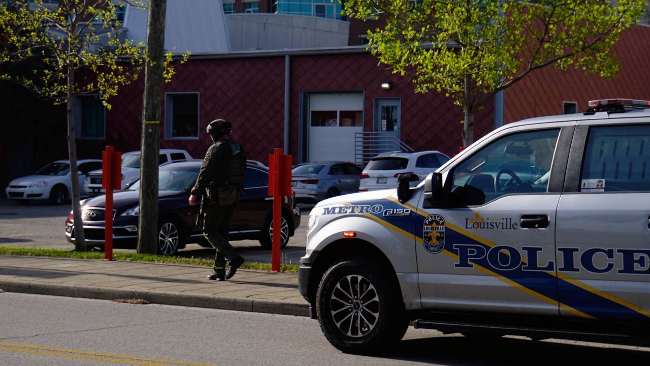 A Louisville Metro police officer walks toward the scene of an active shooting in downtown Louisville, Ky. (Spectrum News 1/Mason Brighton)