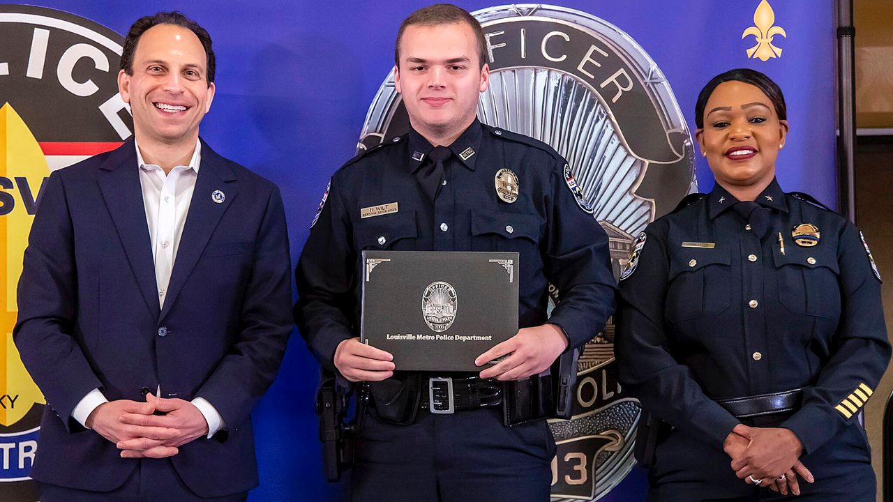 In this photo provided by the Louisville Metro Police Department, from left, Louisville Mayor Craig Greenberg, Officer Nickolas Wilt and Louisville Metro Interim Police Chief Jacquelyn Gwinn-Villaroel pose for a photo, in Louisville, Ky., March 31, 2023. (Louisville Metro Police Department)