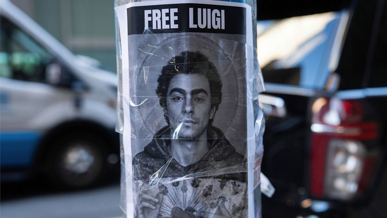 A poster depicting Luigi Mangione hangs outside the New York Hilton Midtown hotel, Thursday, Dec. 12, 2024, in New York. (AP Photo/Julia Demaree Nikhinson)