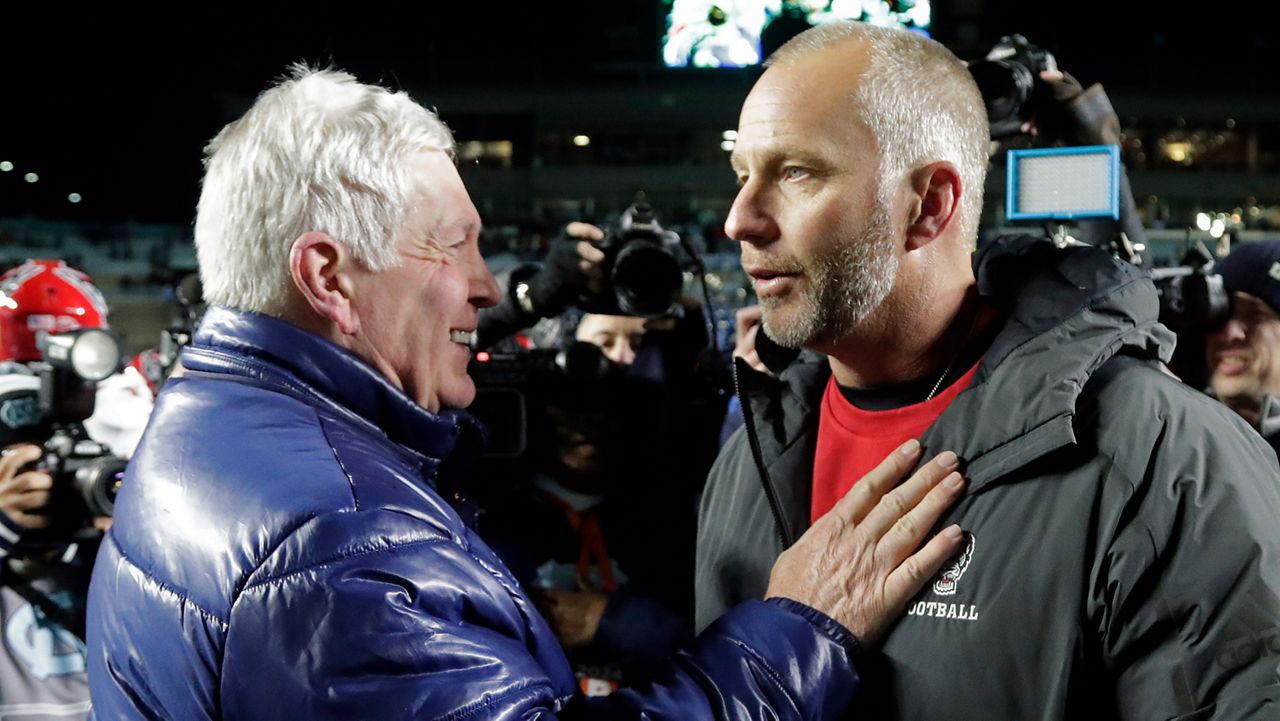 N.C. State head coach Dave Doeren, right, talks with North Carolina head coach Mack Brown, left, after an NCAA college football game, Saturday, Nov. 30, 2024, in Chapel Hill, N.C. (AP Photo/Chris Seward)