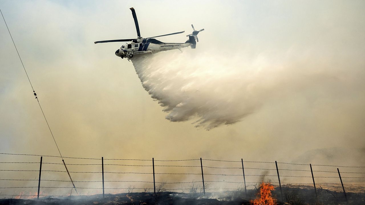 A helicopter drops water on the Madre Fire as it burns along Highway 166 on Thursday, July 3, 2025, in San Luis Obispo County, Calif. (AP Photo/Noah Berger)