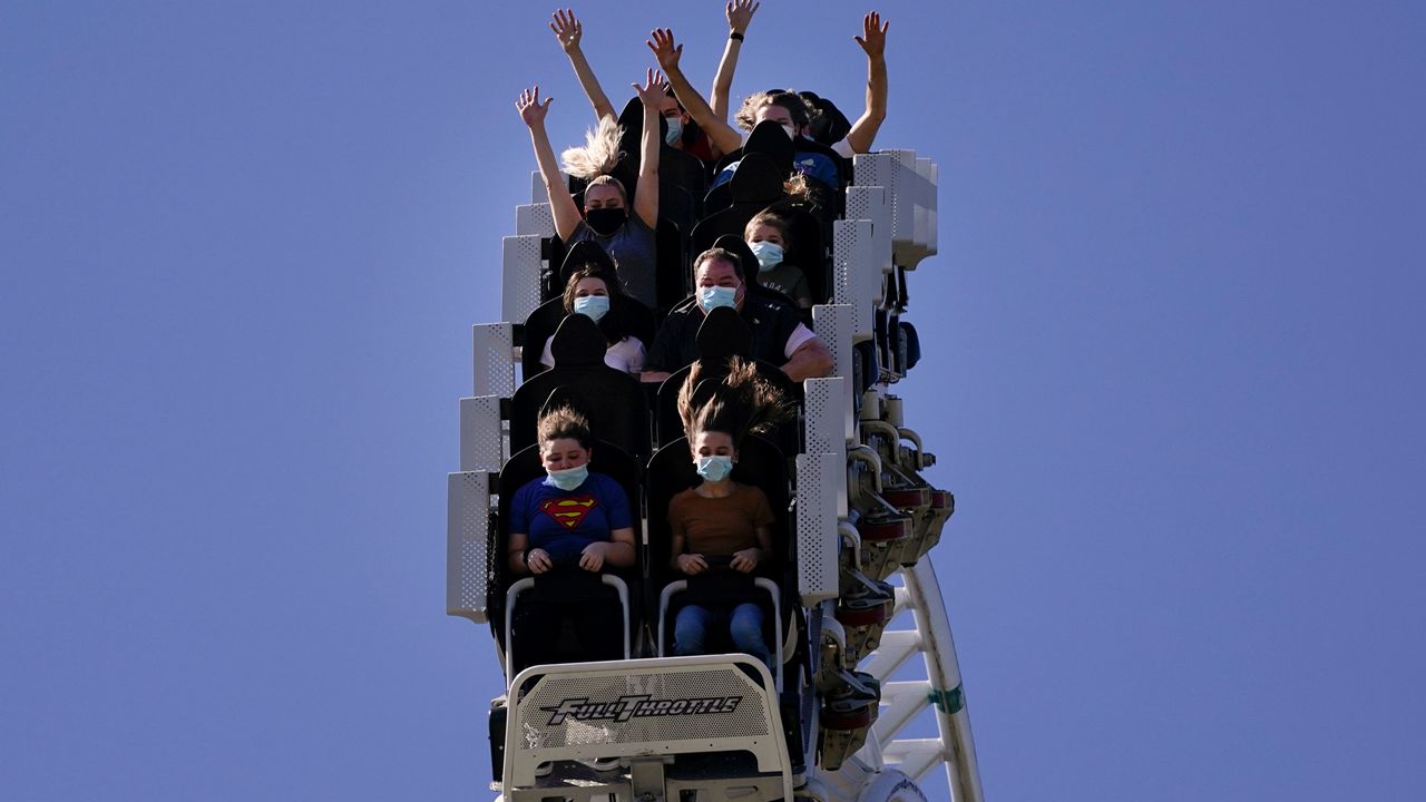 Visitors wearing masks ride on a roller coaster at Six Flags Magic Mountain on its first day of reopening to members and pass holders in Valencia, Calif., Thursday, April 1, 2021. (AP Photo/Jae C. Hong)