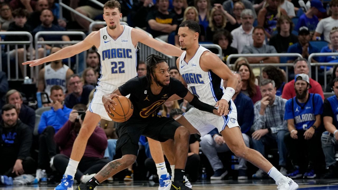Cleveland Cavaliers' Darius Garland, center, looks to get around Orlando Magic's Franz Wagner (22) and Jalen Suggs, right, during the second half of an NBA basketball game, Tuesday, April 4, 2023, in Orlando, Fla. (AP Photo/John Raoux)