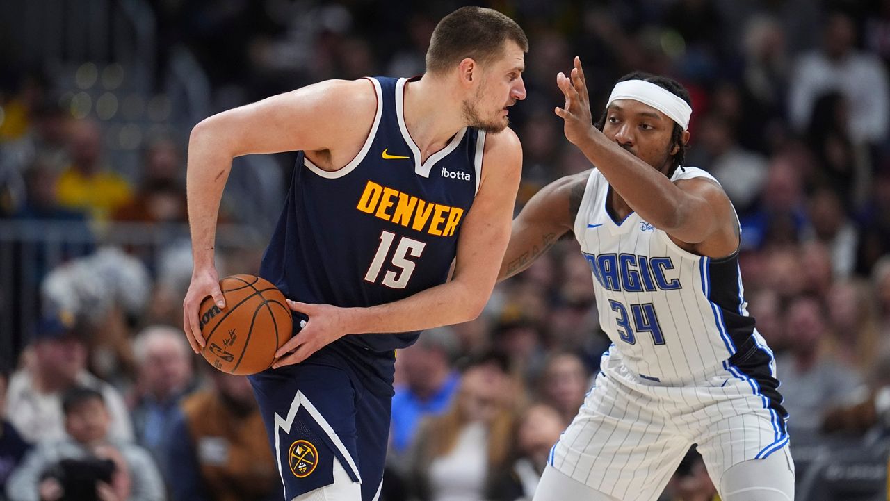 Denver Nuggets center Nikola Jokic, lef,t looks to pass the ball as Orlando Magic center Wendell Carter Jr. defends in the first half of an NBA basketball game Thursday, Feb. 6, 2025, in Denver. (AP Photo/David Zalubowski)