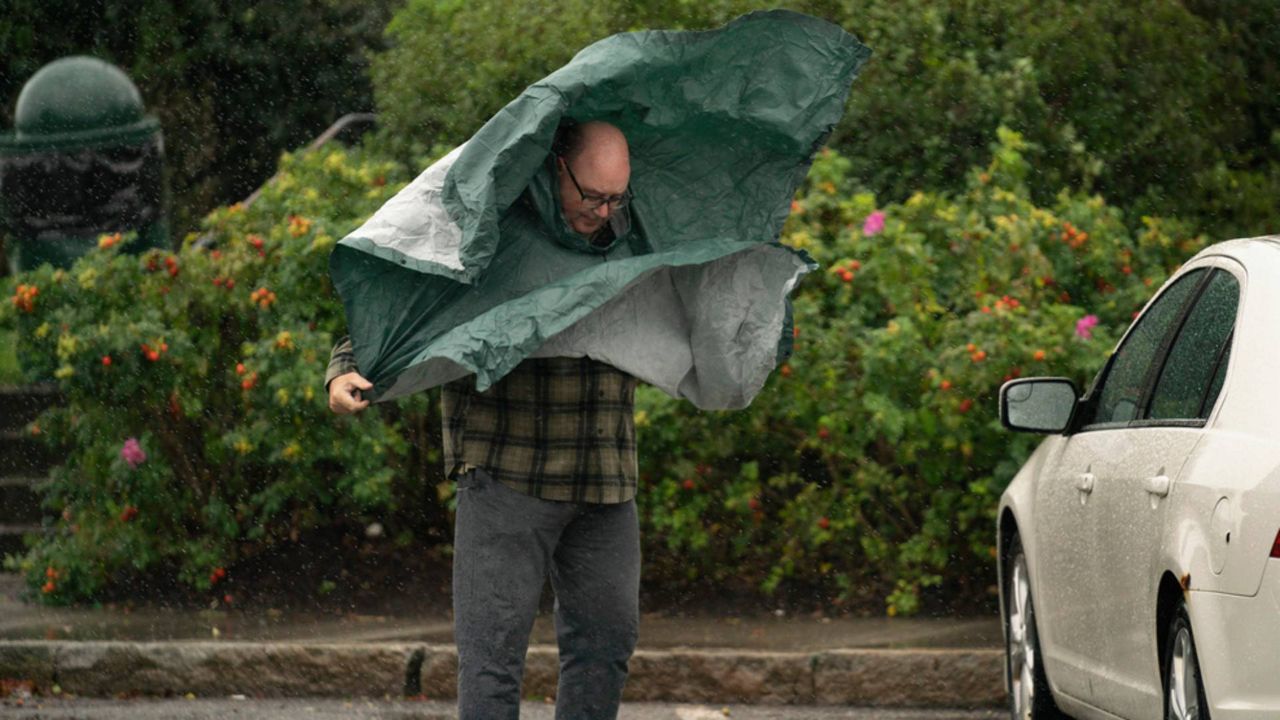 A tourist struggles with his rain poncho in strong wind as weather associated with Hurricane Lee hits the region, Saturday, Sept. 16, in Bar Harbor, (AP Photo/Robert F. Bukaty)