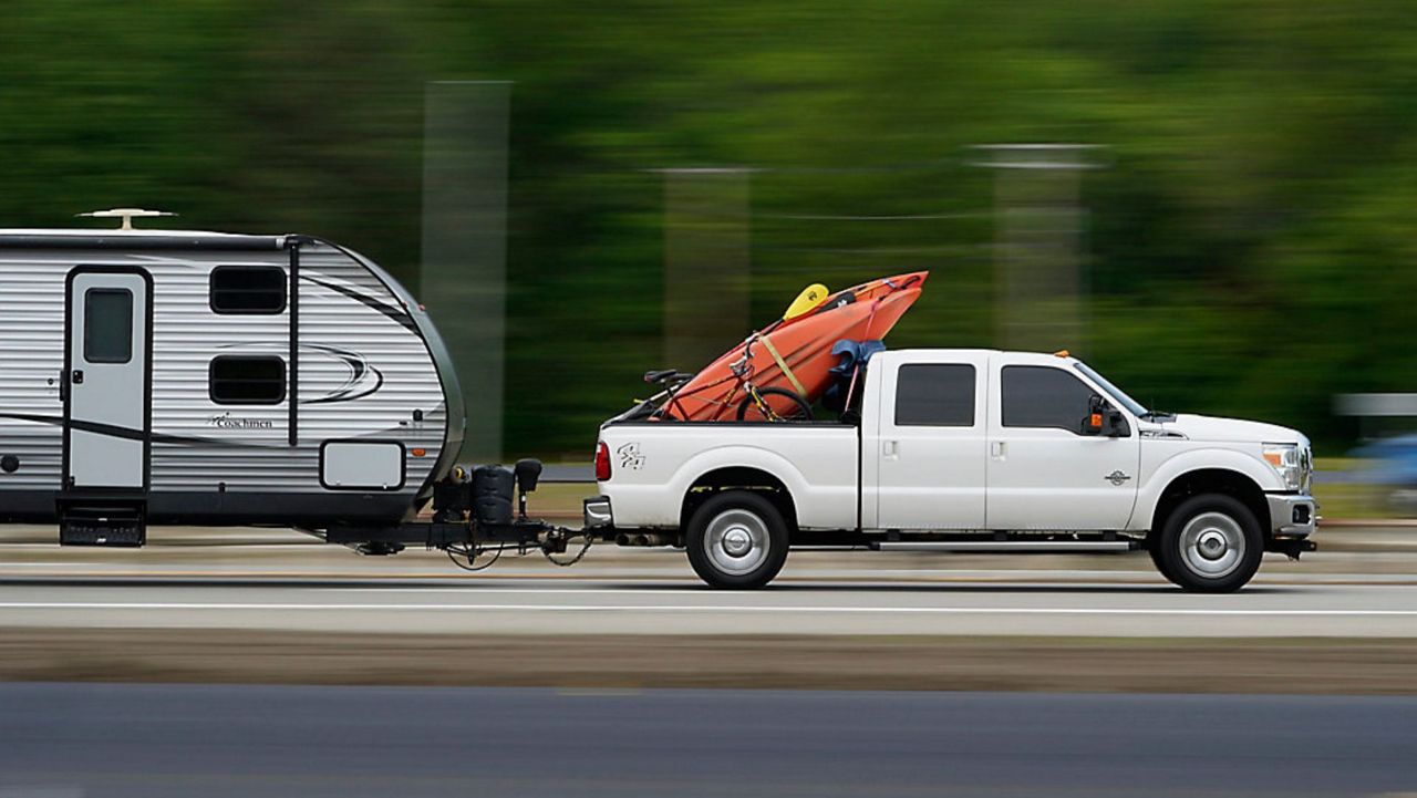 A motorist pulling a camper and carrying kayaks and bikes travels on the Maine Turnpike, Friday, May 28, 2021, in Kennebunk, Maine. The state expects a large increase in the number of out-of-state visitors over last year when the COVID-19 pandemic forced a lot of businesses to close. (AP Photo/Robert F. Bukaty)