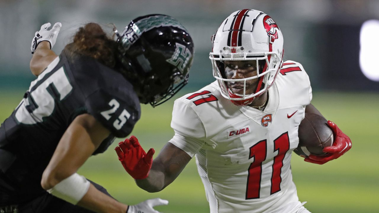 Western Kentucky wide receiver Malachi Corley (11) prepares to fend off Hawaii defensive back Matagi Thompson (25) during the first half of an NCAA college football game Saturday, Sept. 3, 2022, in Honolulu. (AP Photo/Marco Garcia)