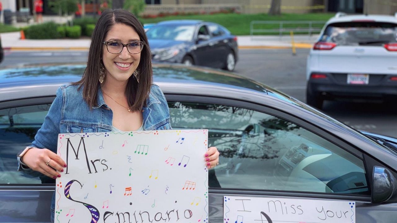 A teacher holding a sign