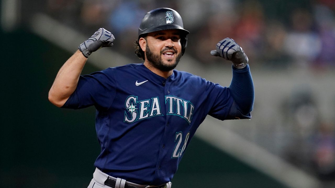 Seattle Mariners' Eugenio Suarez, left, holds a trident in the