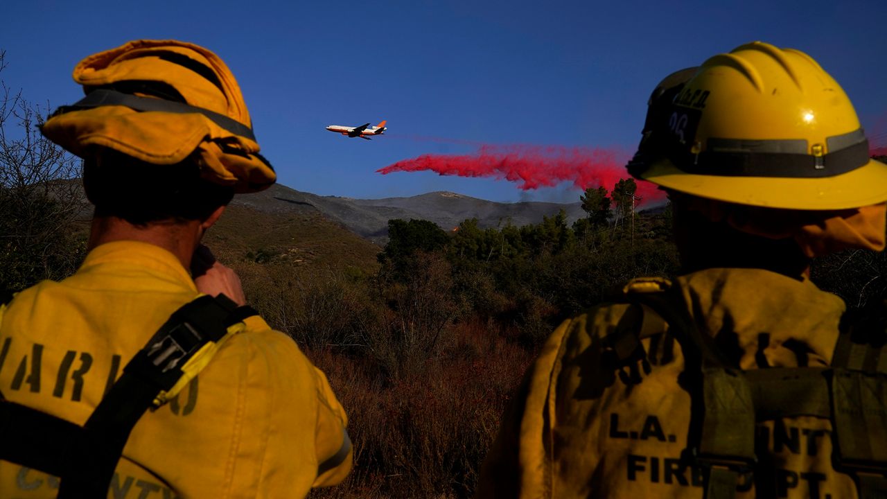 Fire crews from the Los Angeles County Fire Department watch an air tanker drop retardant onto the Martindale Fire, Monday, Sept. 28, 2020, in Santa Clarita, Calif. (AP Photo/Marcio Jose Sanchez)
