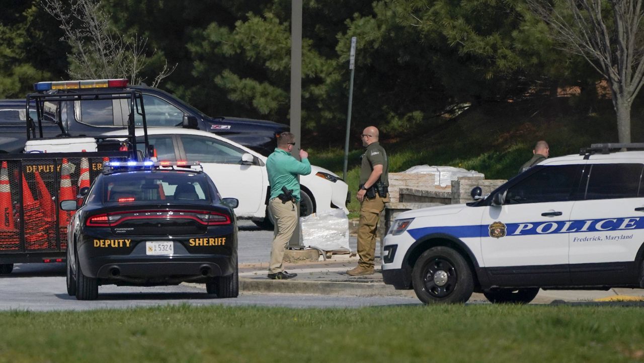 Police talk near the scene of a shooting at a business park in Frederick, Md., on Tuesday. (AP Photo/Julio Cortez)