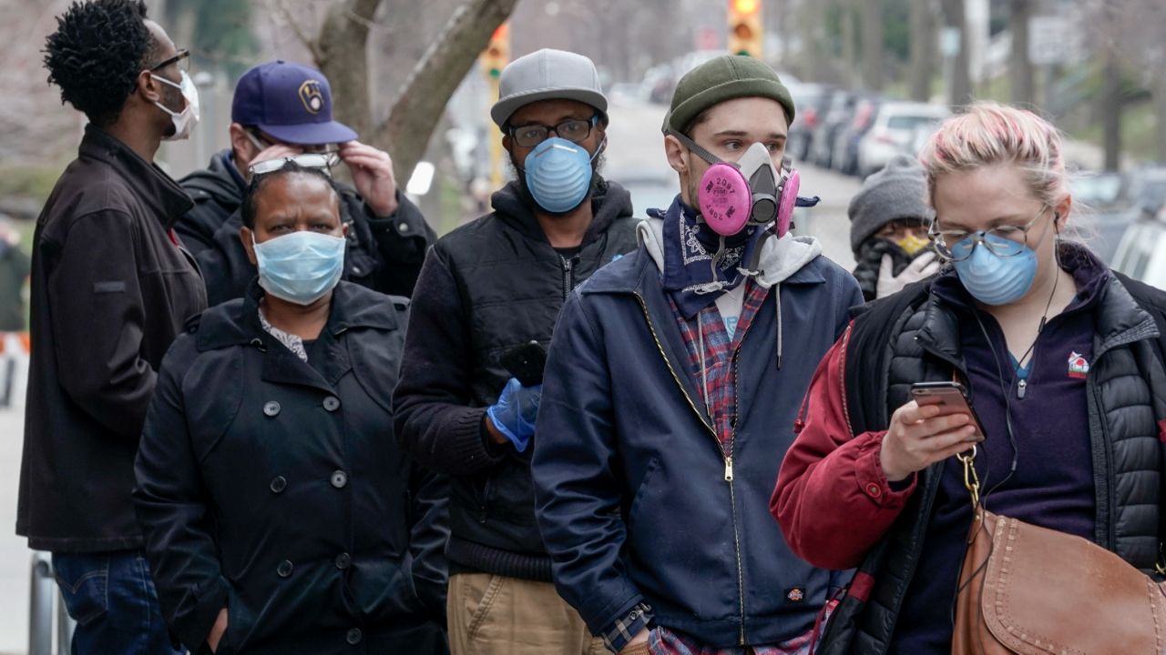 In this April 7, 2020, file photo, voters masked against coronavirus line up Wisconsin's primary election in Milwaukee.