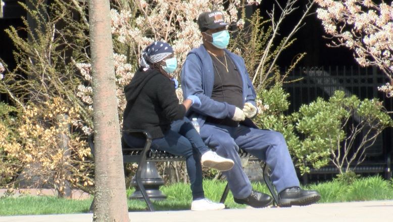 People wear facial coverings in a park in this file image. (Associated Press)