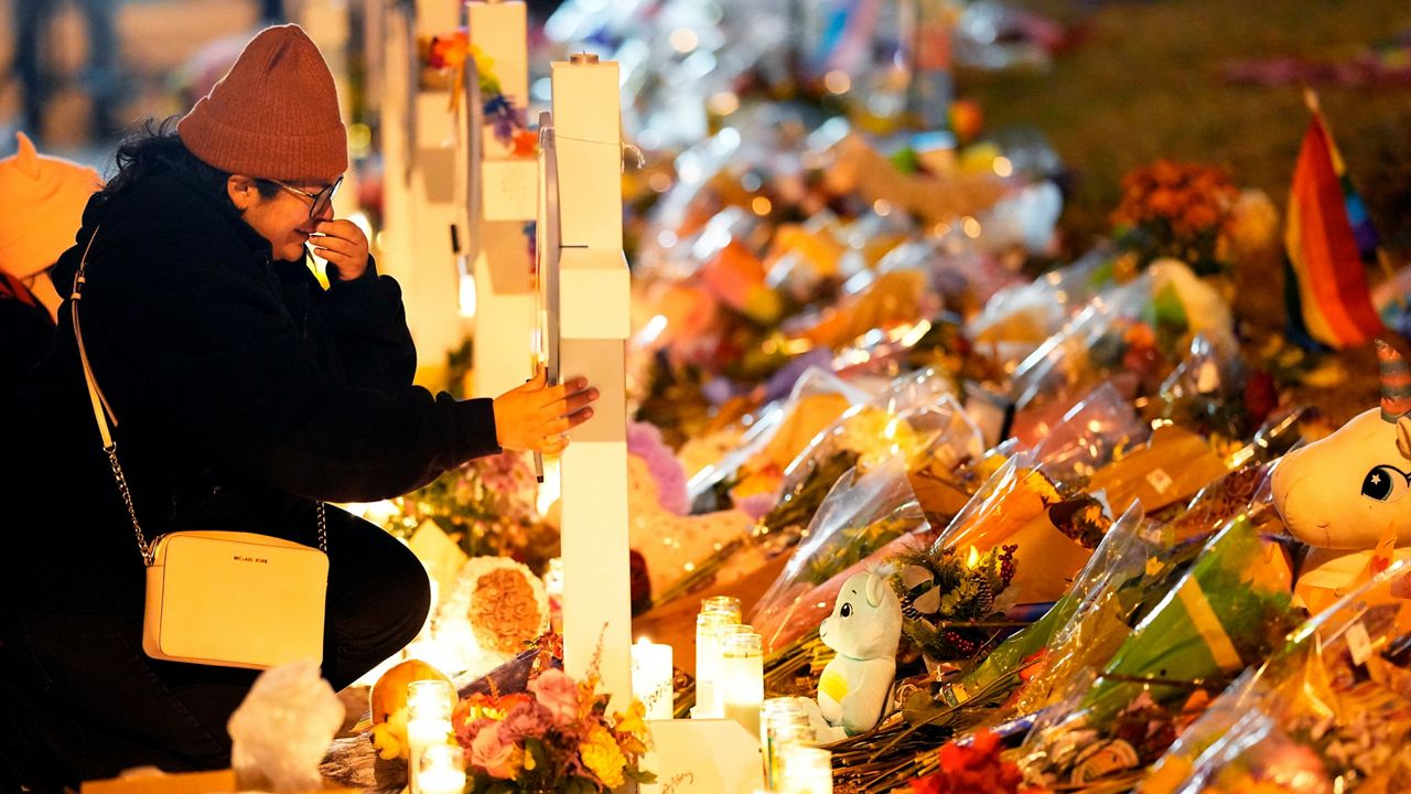 A woman cries at a cross for one of the victims of Saturday's fatal shooting at Club Q during a candlelight vigil on a corner near the site of the gay bar on Nov. 21, 2022 in Colorado Springs.