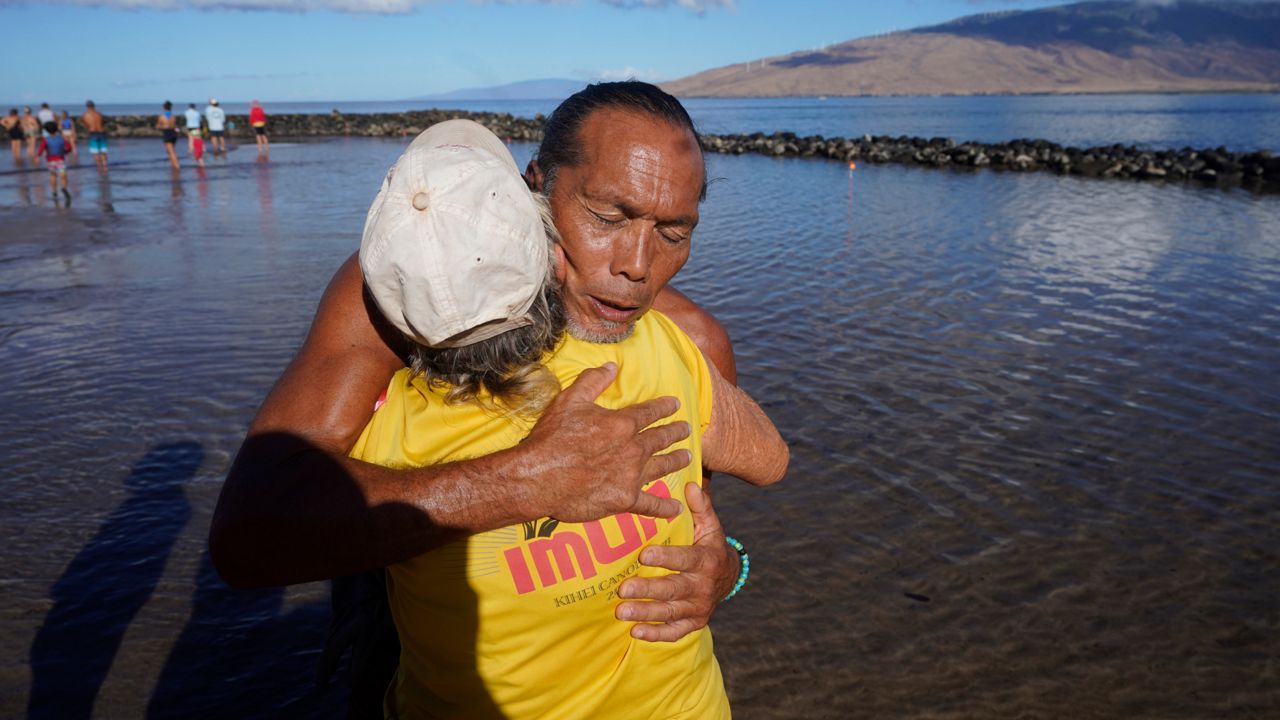 Vicente Ruboi receives a hug after performing a blessing to greeting the day Tuesday, Aug. 15, 2023, in Kihei, Hawaii. (AP Photo/Rick Bowmer)