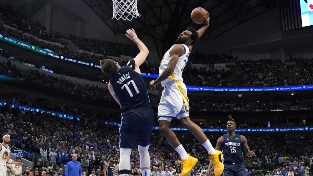 Golden State Warriors forward Andrew Wiggins (22) dunks the ball over Dallas Mavericks guard Luka Doncic (77) during the second half of Game 3 of the NBA basketball playoffs Western Conference finals, Sunday, May 22, 2022, in Dallas. (AP Photo/Tony Gutierrez)