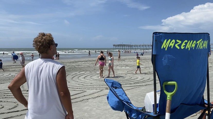 Aaron Gutknecht watches as beachgoers enjoy his work.  (Spectrum News 1/Natalie Mooney)