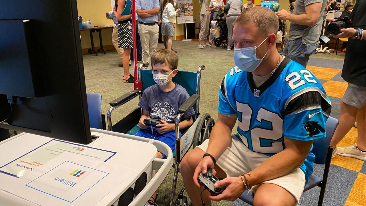 Christian McCaffrey and a Levine Children's patient playing video games.