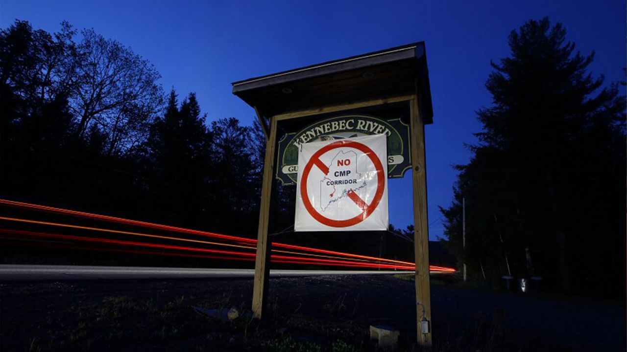 In this Tuesday, May 28, 2019 photo a sign in protest of Central Maine Power's controversial hydropower transmission corridor is stretched across a business sign in The Forks, Maine. (Photo by Robert F. Bukaty / AP)