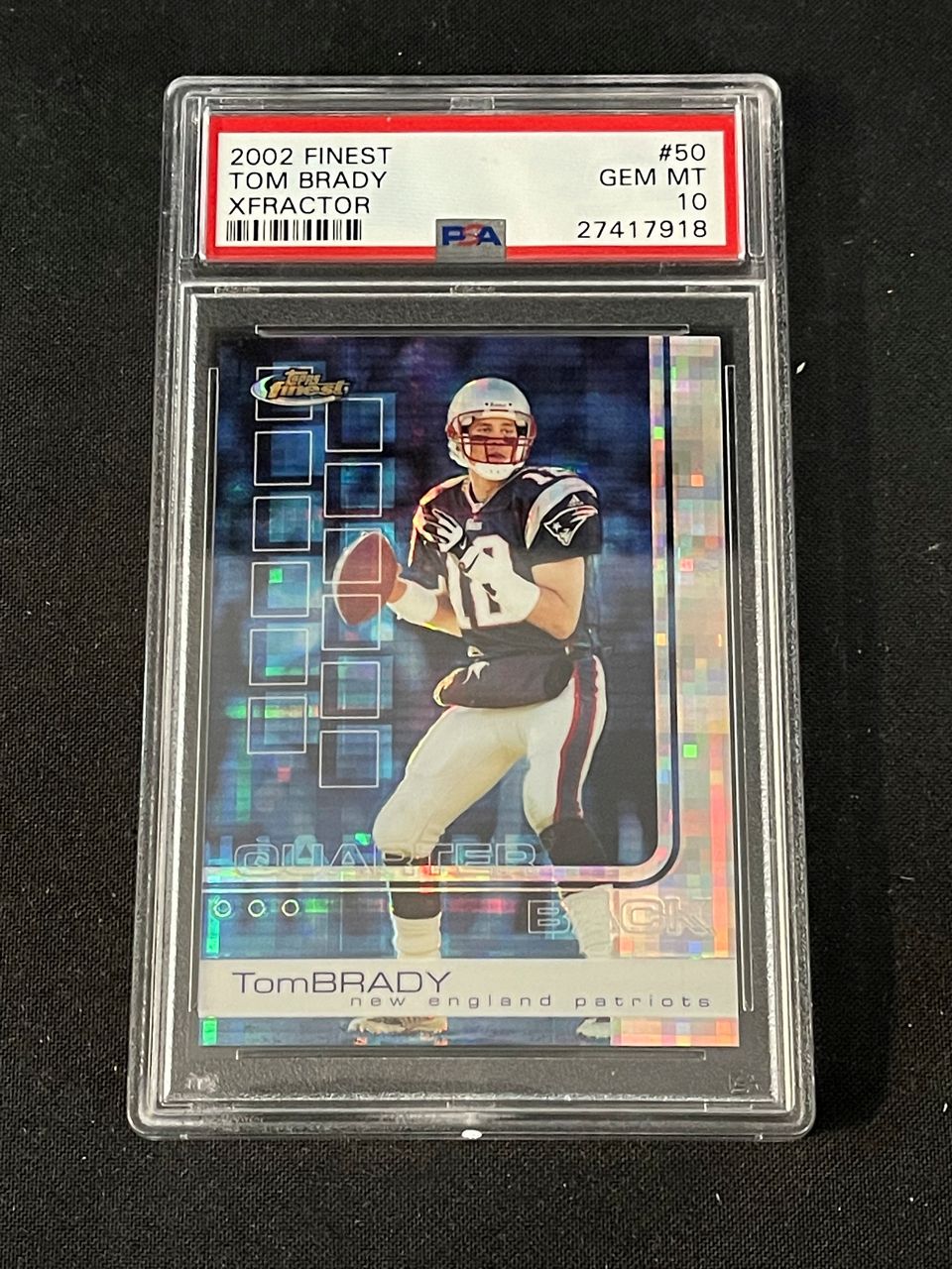 In this photo provided by Saco River Auction LLC, a 2002 Topps Finest X-Fractor card showing football quarterback Tom Brady rests inside a transparent case, Wednesday, Jan. 19, 2022, in Gorham, Maine. Troy Thibodeau from Saco River Auction estimates the card will fetch six figures when it's auctioned on Jan. 31. (Photo by Troy Thibodeau/Saco River Auction LLC via the Associated Press).