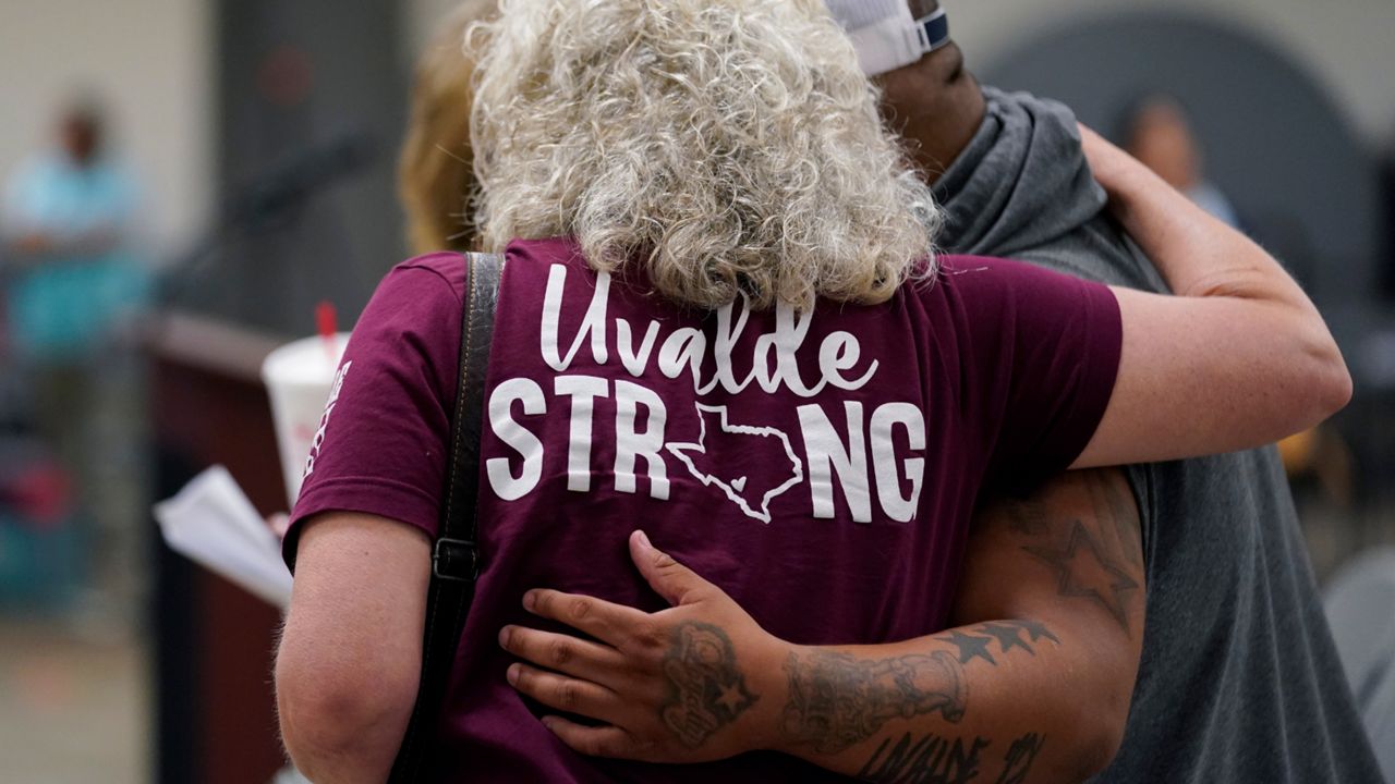 A woman wearing a Uvalde strong shirt embraces another man. (Associated Press)