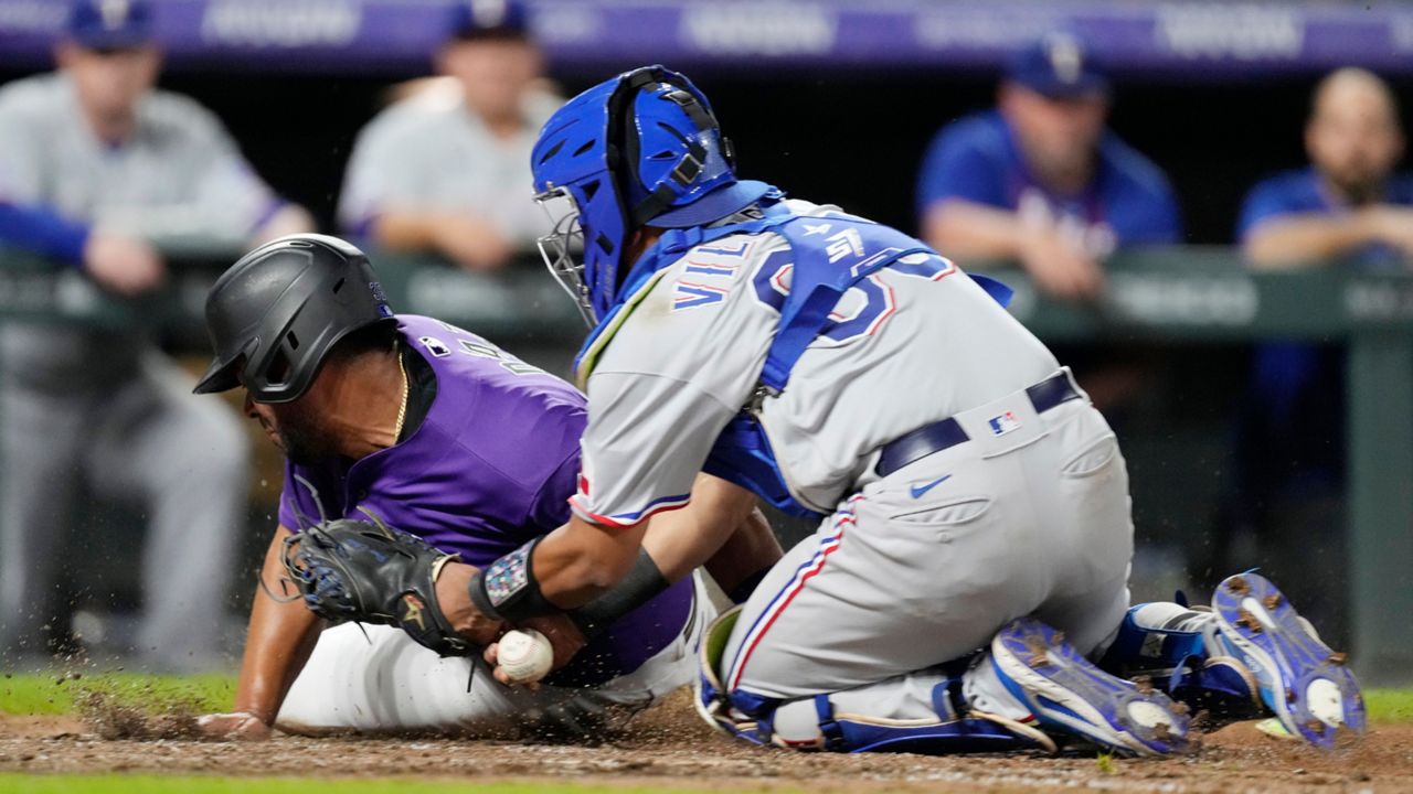 Texas Rangers catcher Meibrys Viloria, right, loses the ball after tagging out Colorado Rockies' Elias Diaz as he tries to score in the eighth inning of a baseball game Tuesday, Aug. 23, 2022, in Denver. (AP Photo/David Zalubowski)