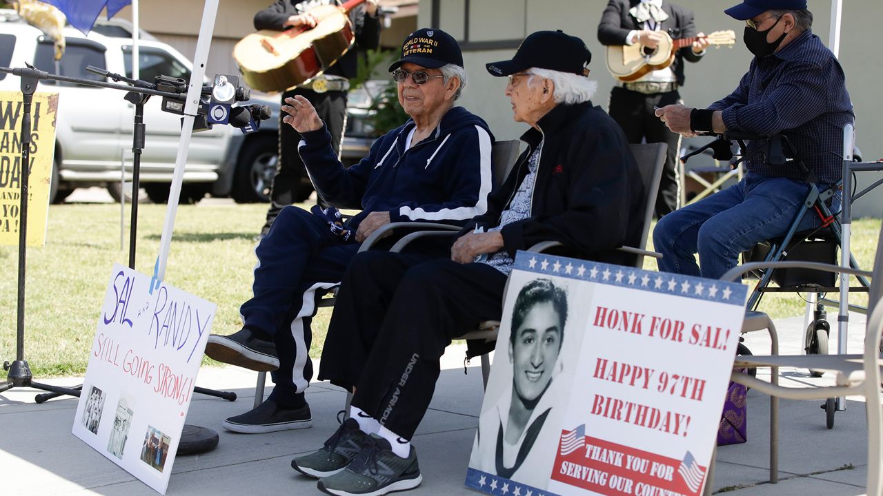 WWII veterans Randy Zepeda, left, and Salvador Guzman wave to supporters as they are serenaded with mariachis to honor Memorial Day Sunday, May 24, 2020, in Whittier, Calif. Members of the Los Angeles Sheriffs Department and various military branches joined the two veterans and their friends and family for a special tribute. Randy served in the Army and Sal in the U.S. Coast Guard during WWII. (AP Photo/Marcio Jose Sanchez)