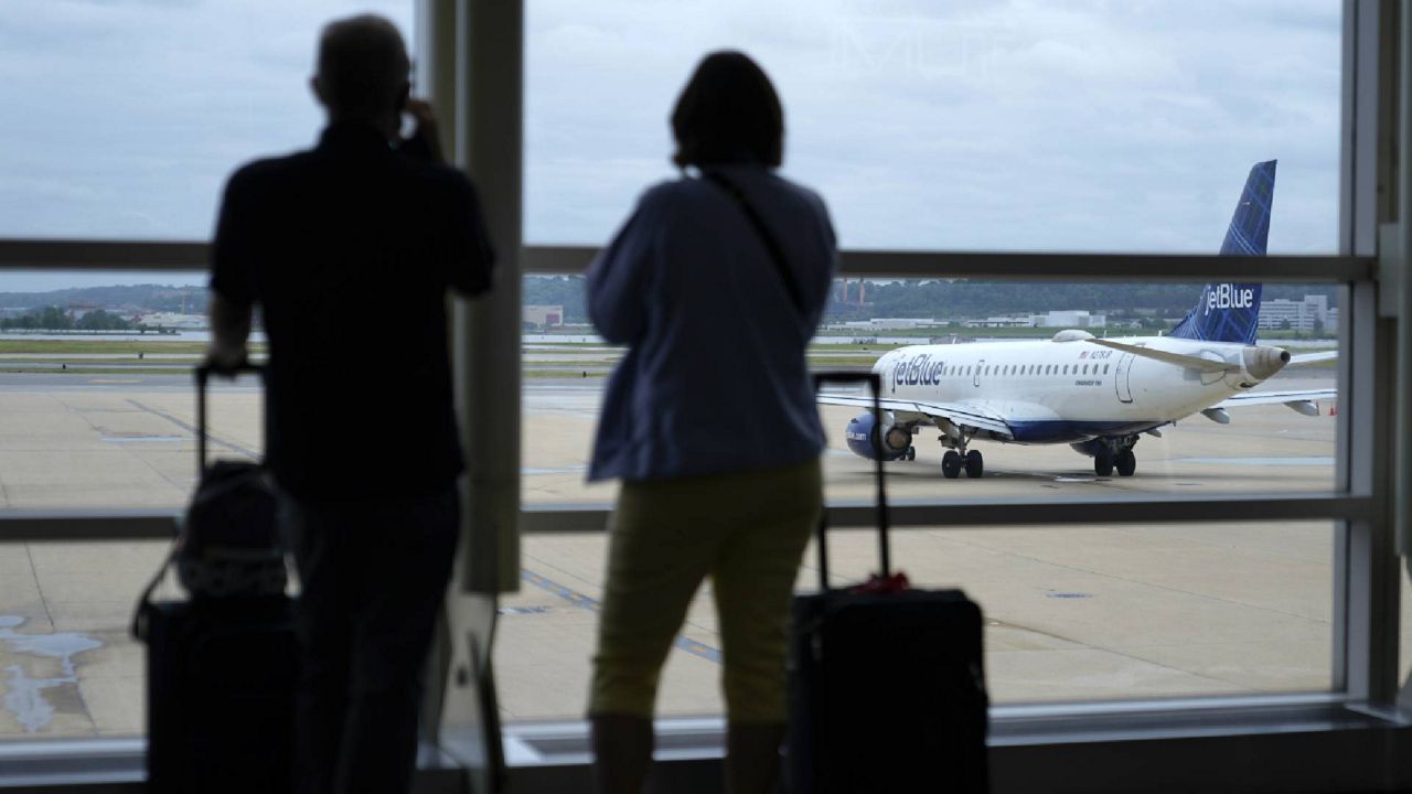 Travelers watch a JetBlue Airways aircraft taxi away from a gate at Ronald Reagan Washington National Airport†ahead of Memorial Day weekend, Tuesday, May 25, 2021, in Arlington, Va. (AP Photo/Patrick Semansky)