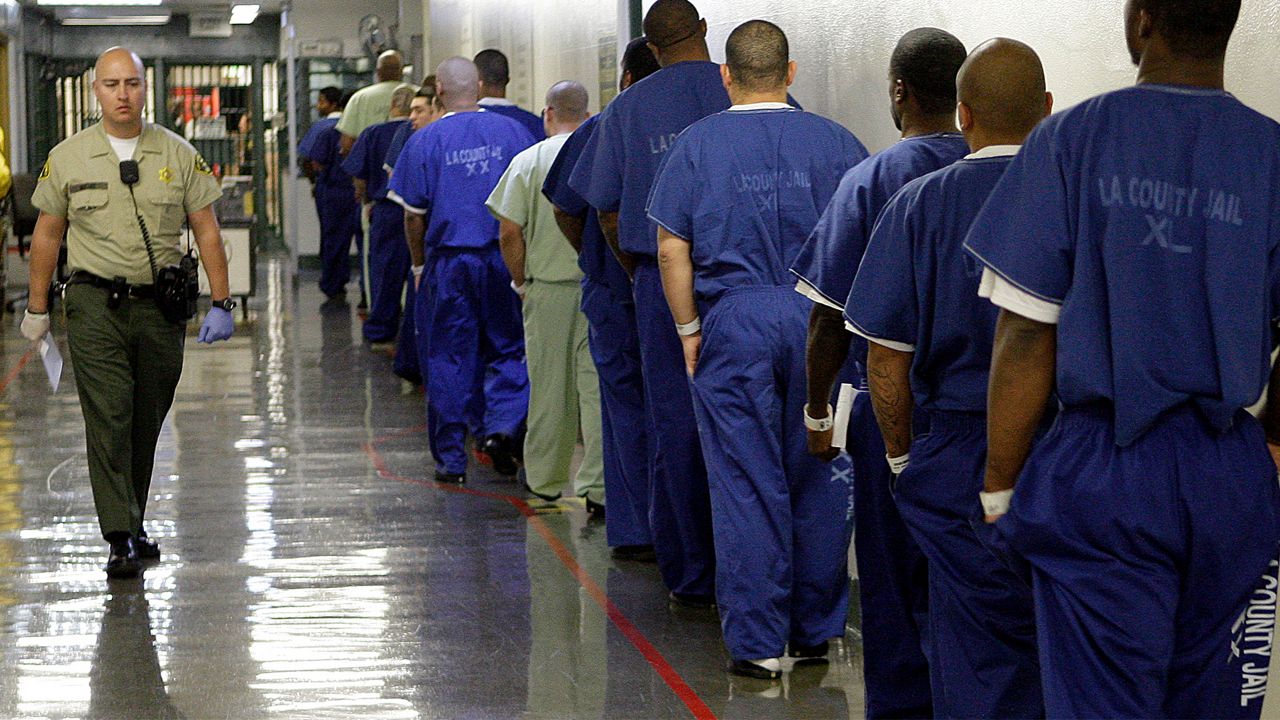 A deputy passes a line of inmates, seen during a tour of the Men's Central Jail, run by the Los Angeles County Sheriff's Department, in downtown Los Angeles Thursday, Oct. 27, 2011. (AP Photo/Reed Saxon)