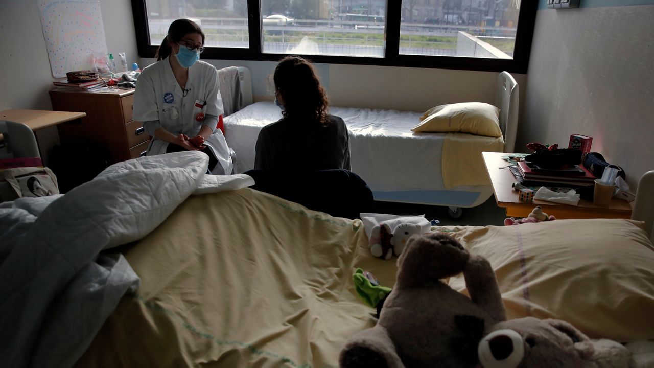 In this Tuesday, March 2, 2021 file photo, psychiatrist Coline Stordeur speaks with a young girl in her room in the pediatric unit of the Robert Debre hospital, in Paris, France. (AP Photo/Christophe Ena, File)