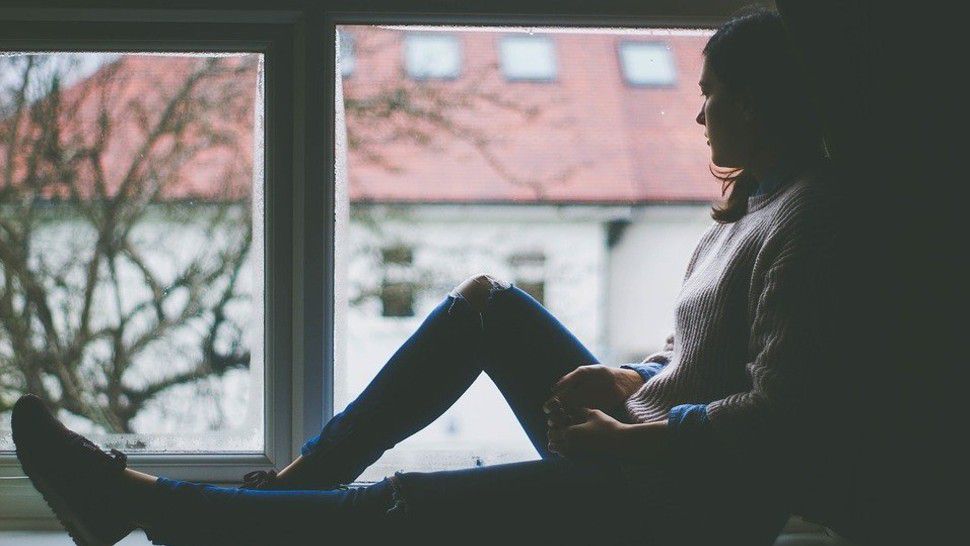 A woman sits by a window in this stock image. (Pixabay)