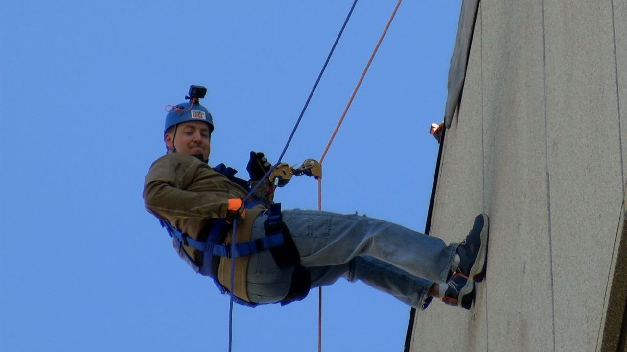 A local thrill-seeker takes in the view while rappelling down the Mercantile Center on Saturday.